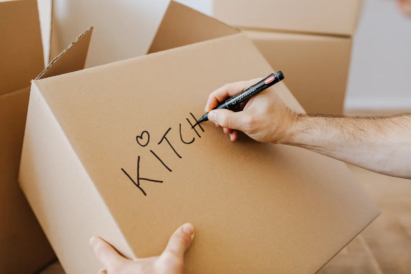Hands labelling a cardboard moving box with a marker