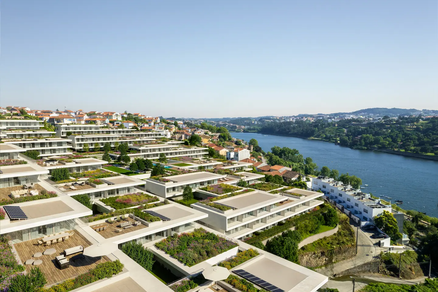 Terraced green roofs and private gardens stepping down toward the river