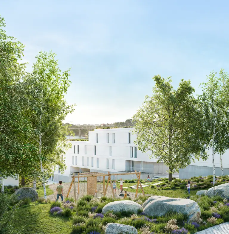 Playground and garden among trees, with the white buildings behind